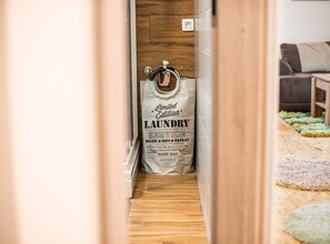 Wasmand met tekst die duidt op een premium service, geplaatst in een gang met houten vloer en een zichtbaar stopcontact.