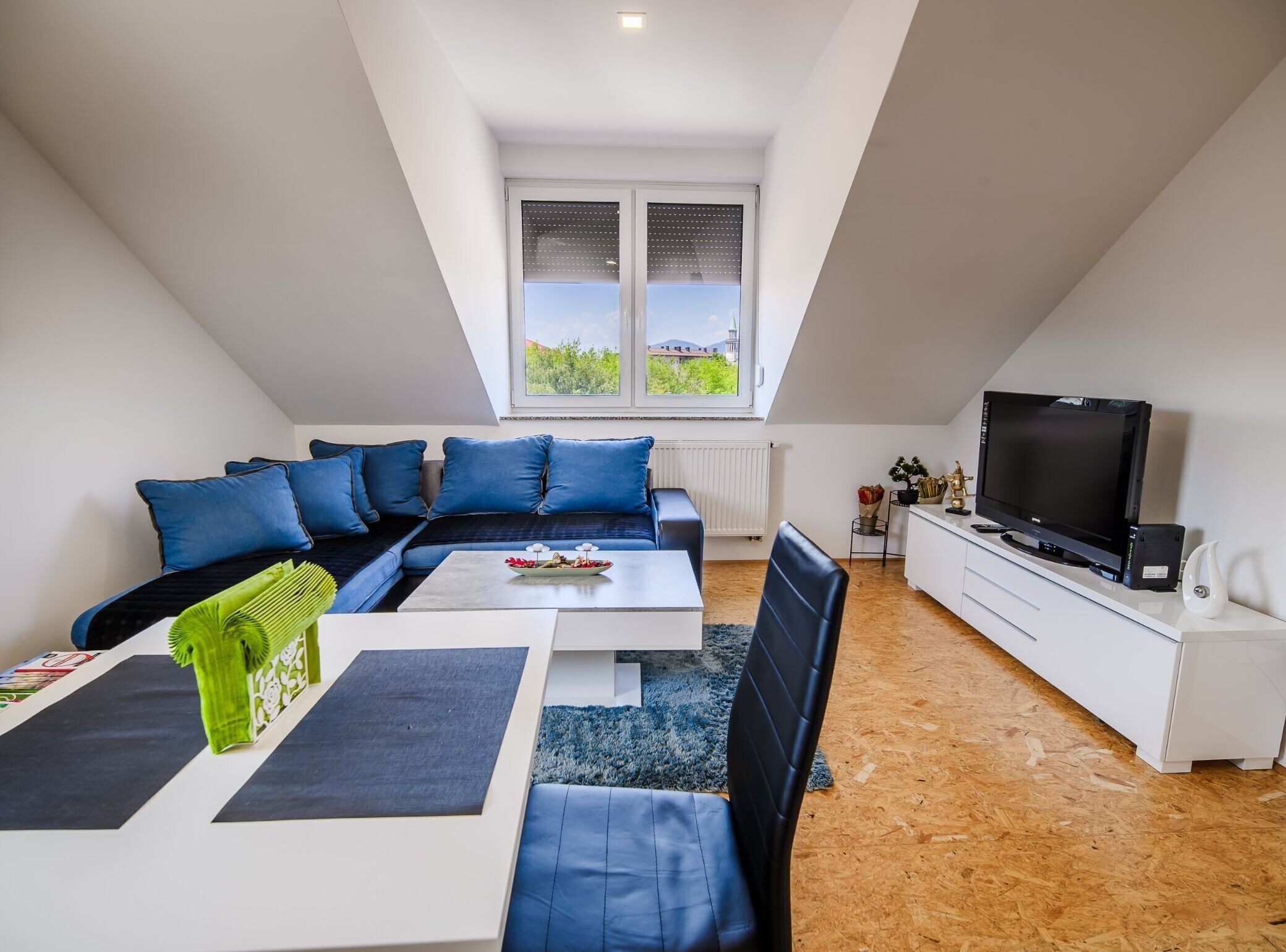 Un moderno loft con un'ampia finestra, una zona divani, un'area pranzo e un televisore.