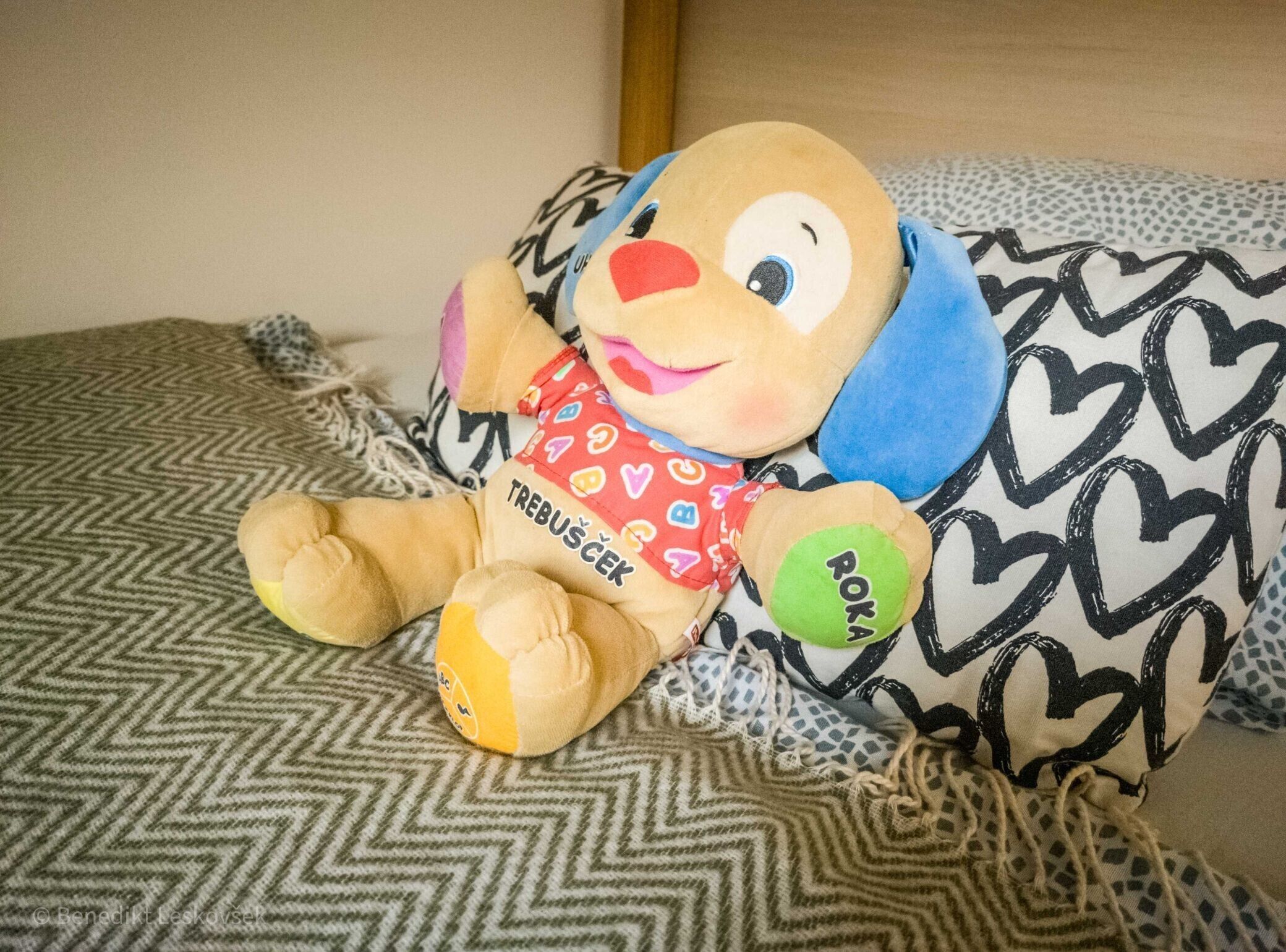 Een zacht knuffeldiertje op een bed met beddengoed met dessin.