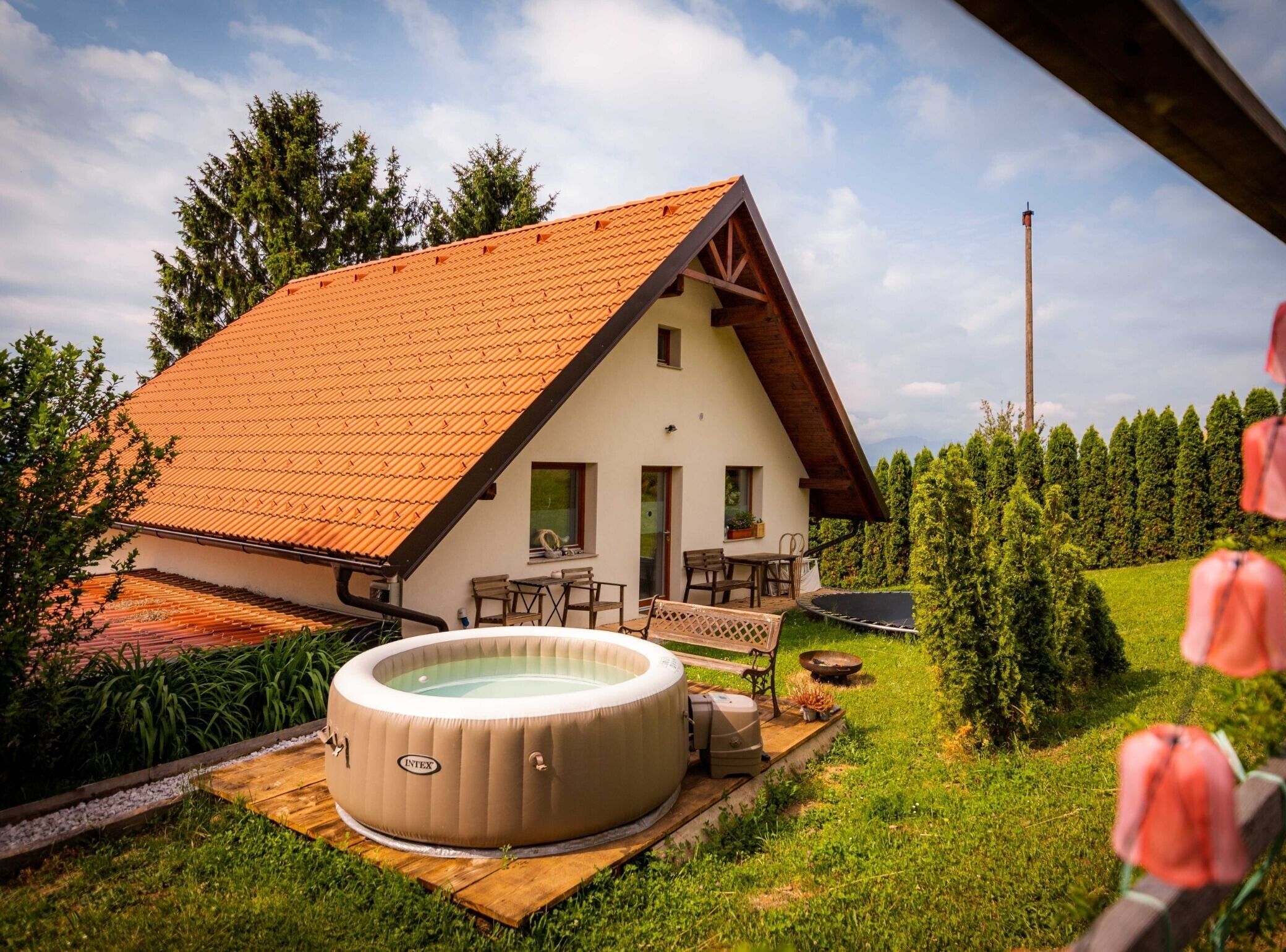 Ein Haus mit Schrägdach, Whirlpool und Garten.