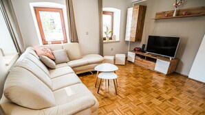 Un soggiorno con un divano modulare beige, un tavolino bianco e una TV su un mobile in legno.