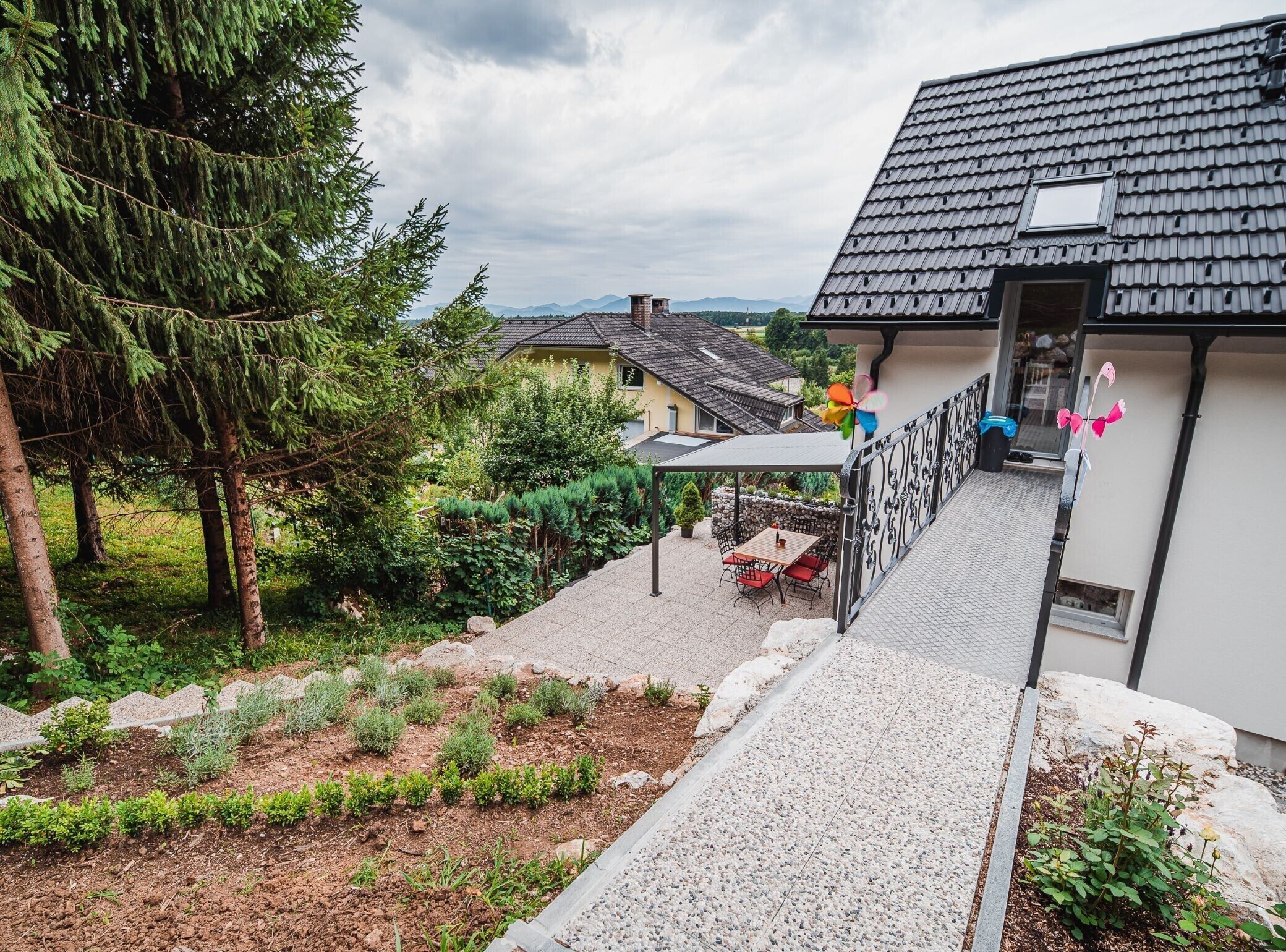 A residential property with a paved patio, a small outdoor seating area, and a garden with various plants.