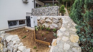 Um edifício moderno com um muro de pedra, unidades de ar condicionado externas e uma área de varanda coberta.