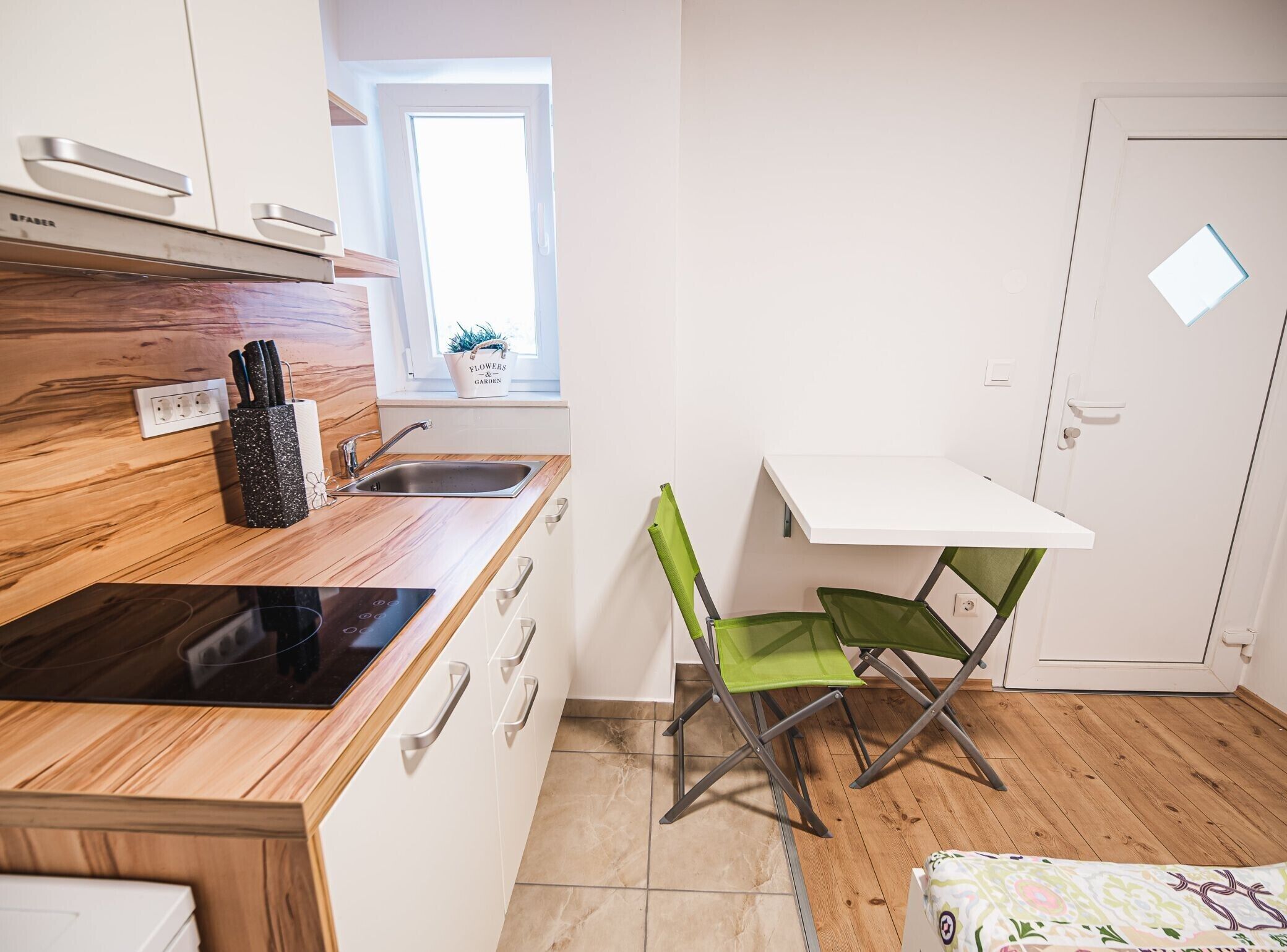Eine kleine Küche mit Holzausziehtisch, Spüle, Tisch und Stuhl.