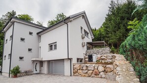 Een tweelaags huis met een gevel van natuursteen, een garage en een verharde oprit.