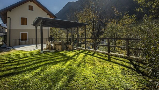 Une maison à deux étages dotée d’un patio couvert, d’une pelouse bien entretenue et offrant une vue sur les montagnes.