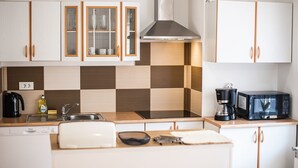 A modern kitchen with white cabinets, a stainless steel range hood, a coffee maker, and a dishwasher.