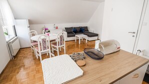 A compact living space with a kitchenette, a dining area, and a seating area with a sofa and chairs.