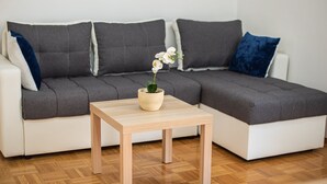 Un soggiorno moderno con un divano a tre posti grigio, un tavolino in legno e un'orchidea in vaso.