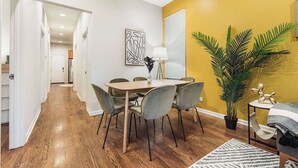 Een eetruimte met een houten tafel en stoelen, een potplant en een lamp.