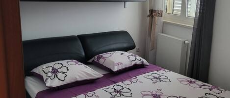 A bedroom with a bed, a wardrobe, and a window with curtains.