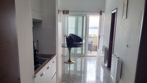 Un couloir comprenant un coin cuisine, un coin repas avec une chaise, et donnant sur l’extérieur.