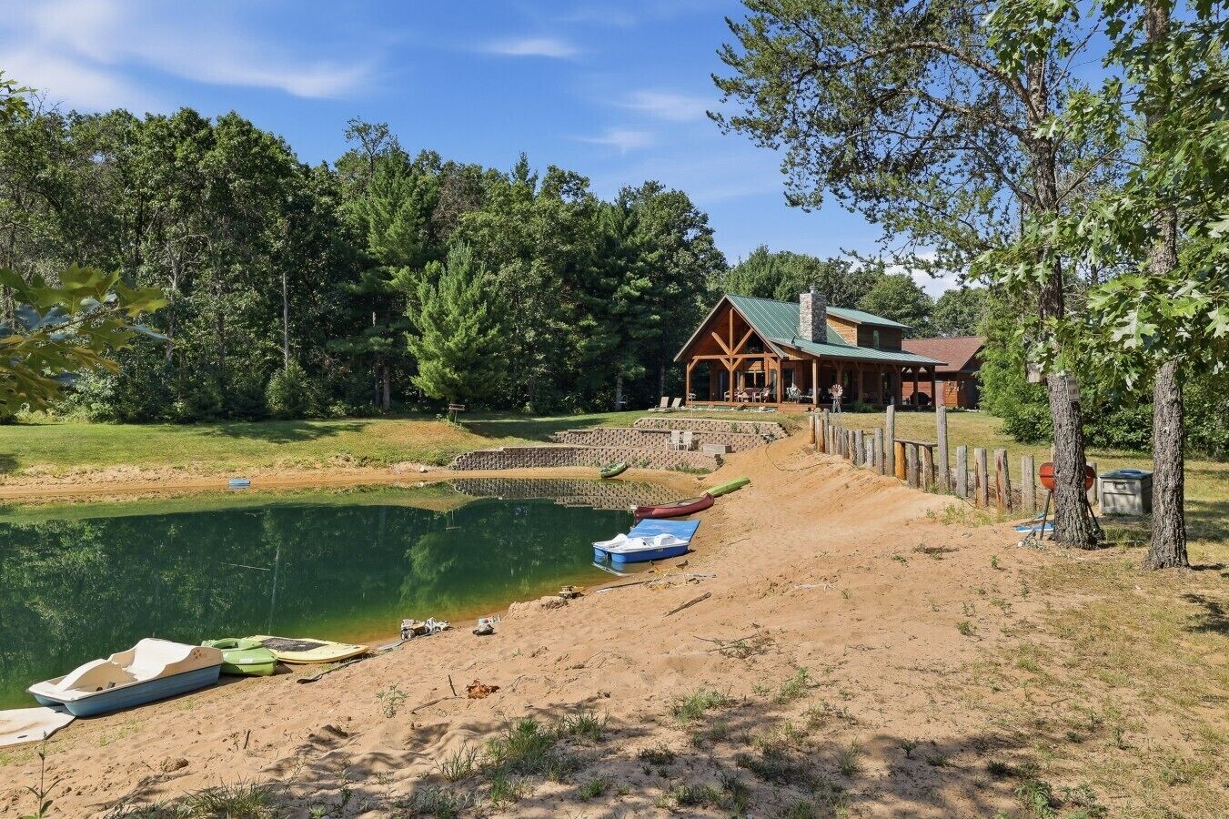 Una cabaña junto al lago con muelle, barcos y valla de madera.