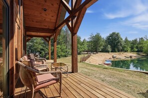 A wooden deck with wicker furniture, a view of a lake, and a covered area with a table and chairs. - Big Woods and Yellow River (Necedah)