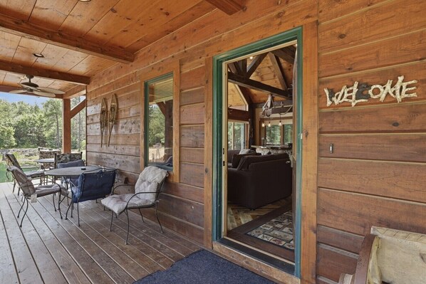 A wooden cabin with a porch, a dining area, and a living room with a sofa and a fireplace. - Big Woods and Yellow River (Necedah)