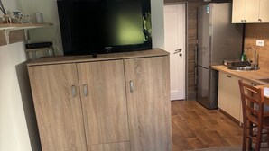 A compact kitchen with a built-in TV, a refrigerator, and a small dining area.
