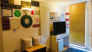 A living room with a sofa, a TV, and various wall decorations. - Charming spacious 2 bed apartment  (London)