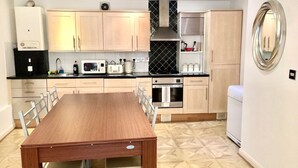 A compact kitchen with a wooden table and chairs, a microwave, toaster, kettle, and a built-in oven. - Charming spacious 2 bed apartment  (London)