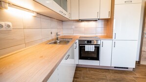 Una cucina moderna con mobili bianchi, un lavello in acciaio inossidabile e un forno integrato.