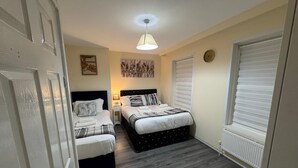 A bedroom with two beds, a ceiling light, a window with blinds, and a radiator. - 3BR House with Free WiFi All Over UK (London)