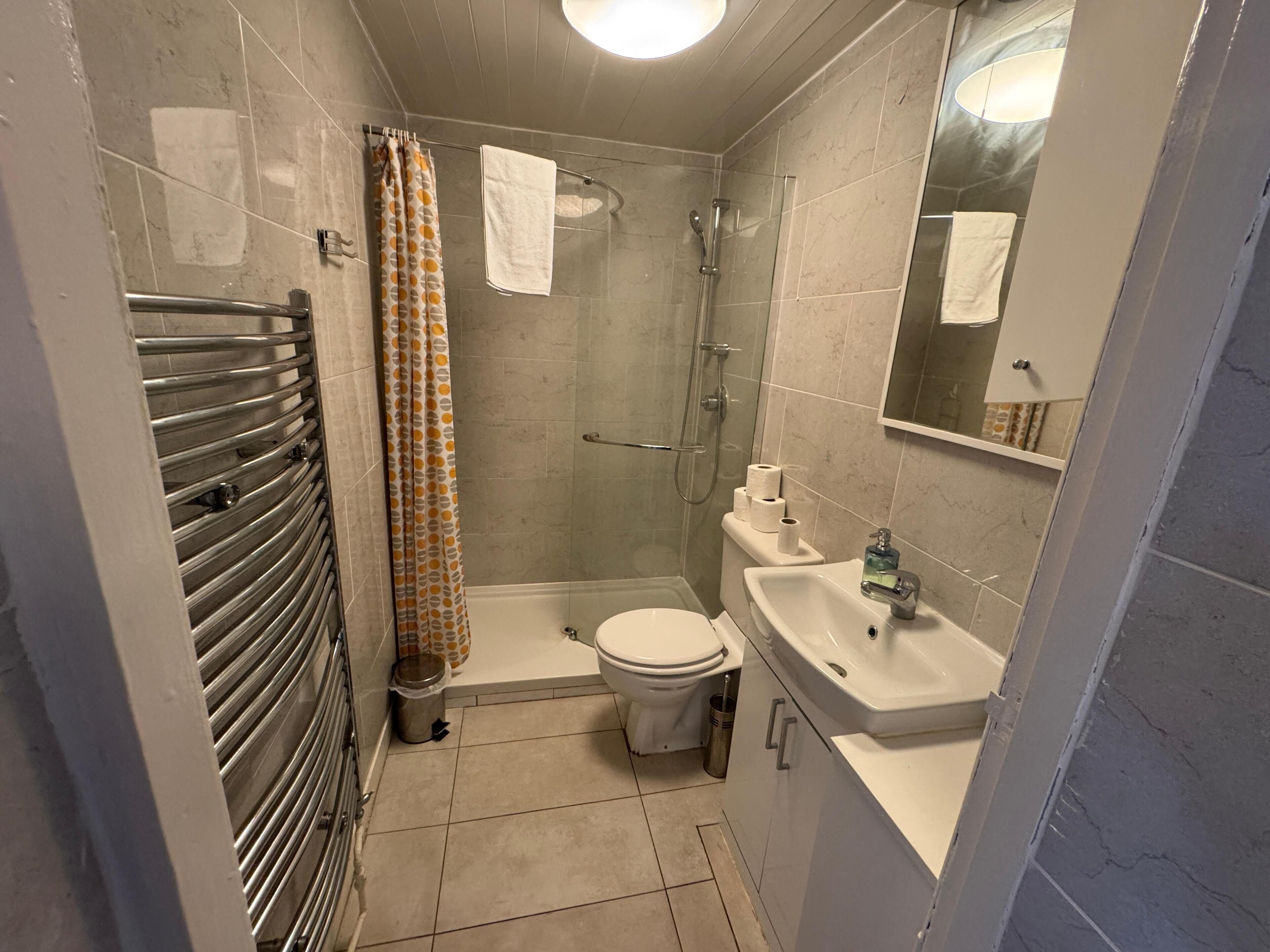 Une petite salle de bain comprenant une douche, des toilettes et un lavabo.
