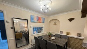 A dining room with a large table, chairs, a chandelier, a fireplace, and a large mirror. - 3BR House with Free WiFi All Over UK (London)