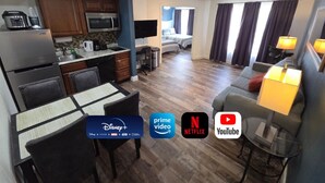 A modern hotel room with a kitchenette, a dining area, a living room with a sofa and a TV, and a bedroom with a bed and curtains. - Disney Family Condo Heated Pool (Kissimmee)