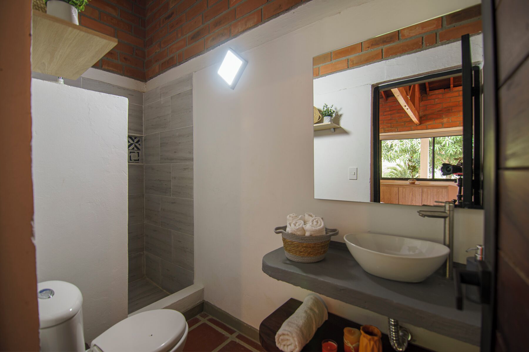 A bathroom with a shower, toilet, sink, and a mirror above the sink.