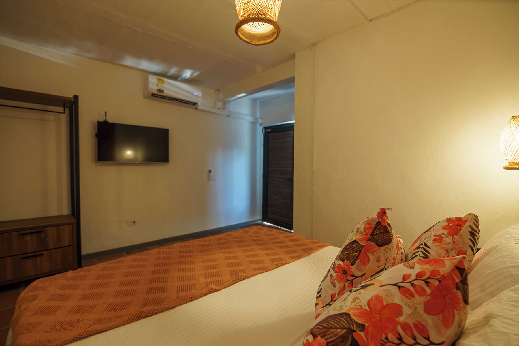 Une chambre à coucher avec un lit, un téléviseur fixé au mur et un appareil de climatisation.