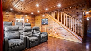 Ein gemütliches Zimmer mit einer Holztreppe, Ledersesseln und einem gerahmten Bild an der Wand.