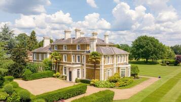 A large, multi-story building with a symmetrical facade, surrounded by well-manicured gardens and a golf course.