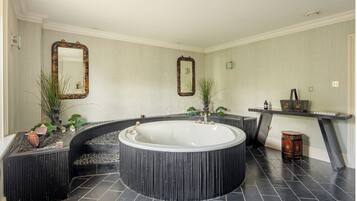 A modern bathroom with a freestanding bathtub, two wall mirrors, and a small table with decorative items.