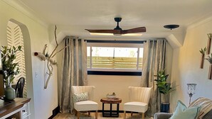 A spacious living room with a wooden floor, two armchairs, a sofa, a dining table, and a ceiling fan. - Carriage house! Close to hospital, firepit, outdoor dining (lima)