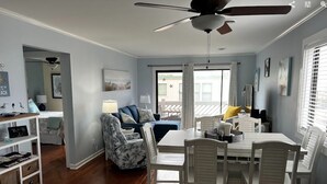 A spacious room with a dining area, a ceiling fan, and a view through a glass door. - Beautiful 2-bedroom condo with ocean views, Wi-Fi, AC, wshr/dryr in Myrtle Beach (Myrtle Beach)