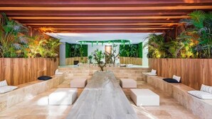 A modern indoor space with a long bench, seating areas, and wooden paneling. - Tulum City Apartments M-209 (Tulum)