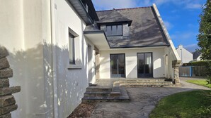 A modern house with a stone exterior, a sloped roof, and a stone pathway leading to the entrance.