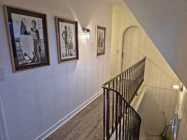 A staircase with a wooden handrail and a light fixture on the wall. - Family home-300m from the sea-Port de Trévignon (Trégunc)