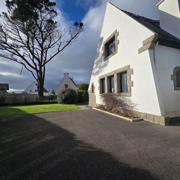 A white building with stone window frames and a paved driveway.