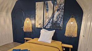 A bedroom with a bed, two wall-mounted lamps, and three framed pictures.