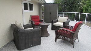 Ein Patio mit Korbmöbeln, darunter zwei Stühle und ein kleiner Tisch.