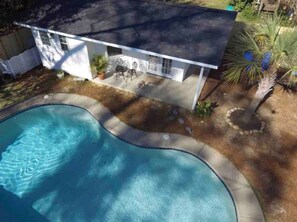 Relax by the oval-shaped pool surrounded by a patio and lush garden.