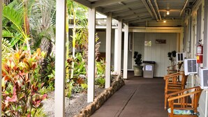 A covered walkway with plants, wooden chairs, and an office area. - Kaua'i Palms Hotel (Lihue)