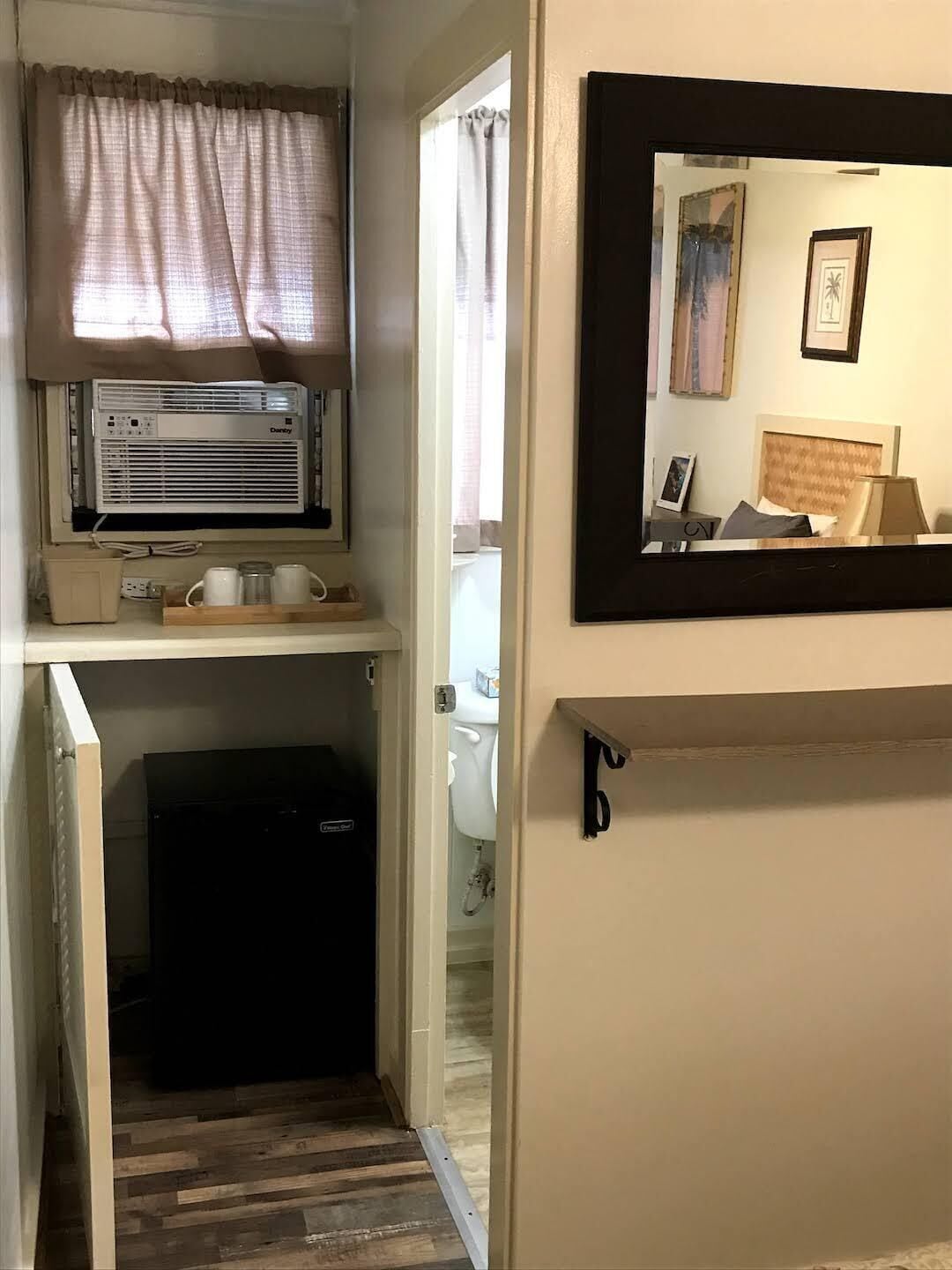 A compact bathroom with a toilet, a small sink, and a window with curtains.