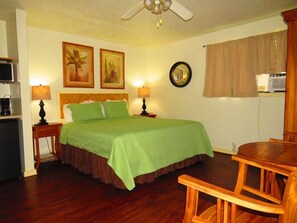 Ein Schlafzimmer mit einem Bett, Nachttischen, einem Deckenventilator, einem Holzstuhl und einem Tisch.