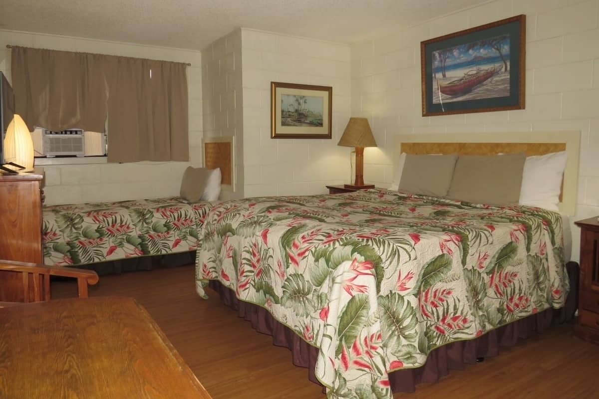 Una habitación con dos camas, una mesa de madera y un cuadro en la pared.