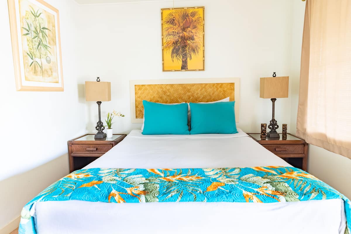 Habitación de hotel con una cama grande, dos mesitas de noche, un cabecero y dos lámparas adosadas a la pared.