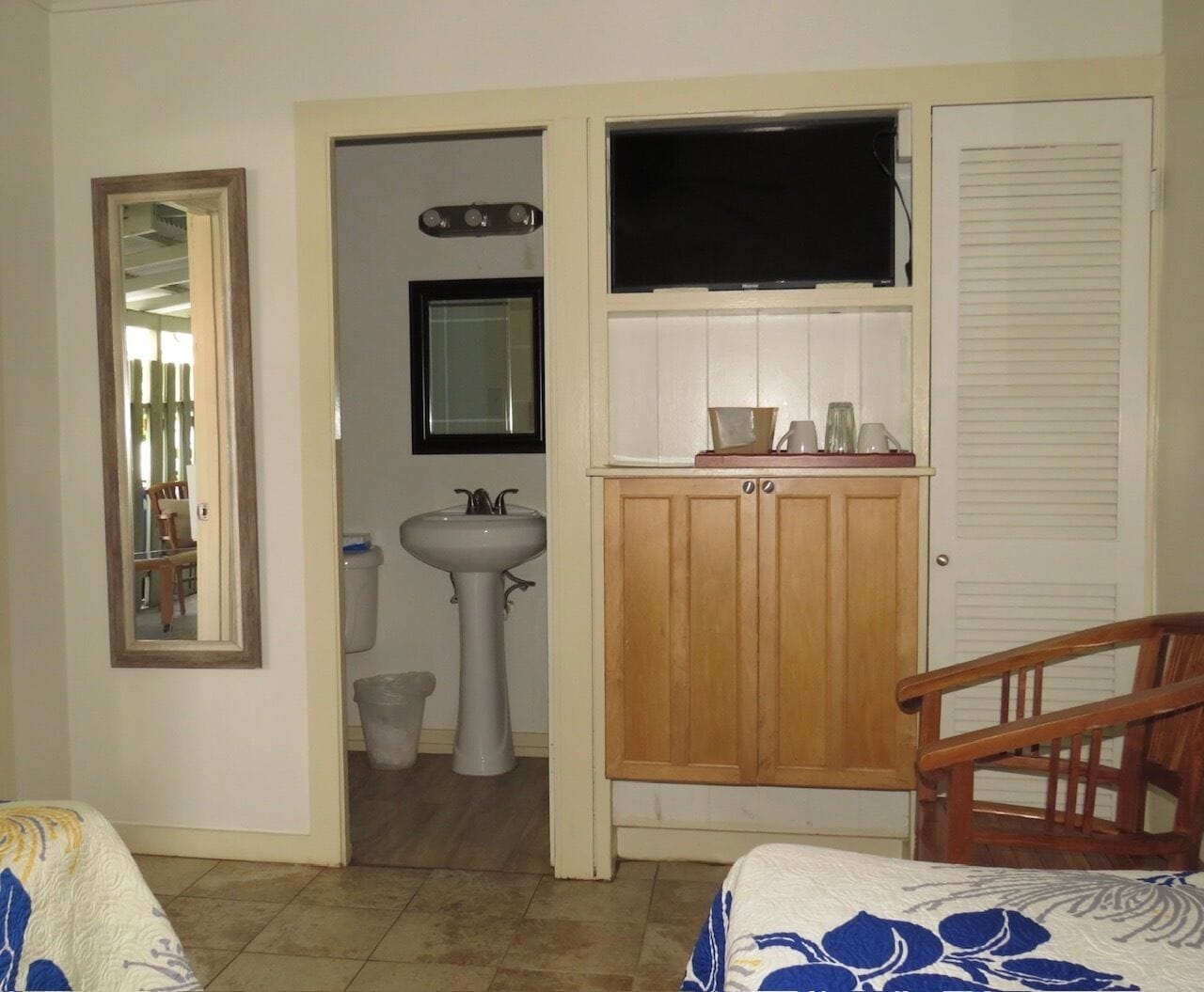 Un dormitorio con una cama, un armario de madera, un lavabo y un espejo.