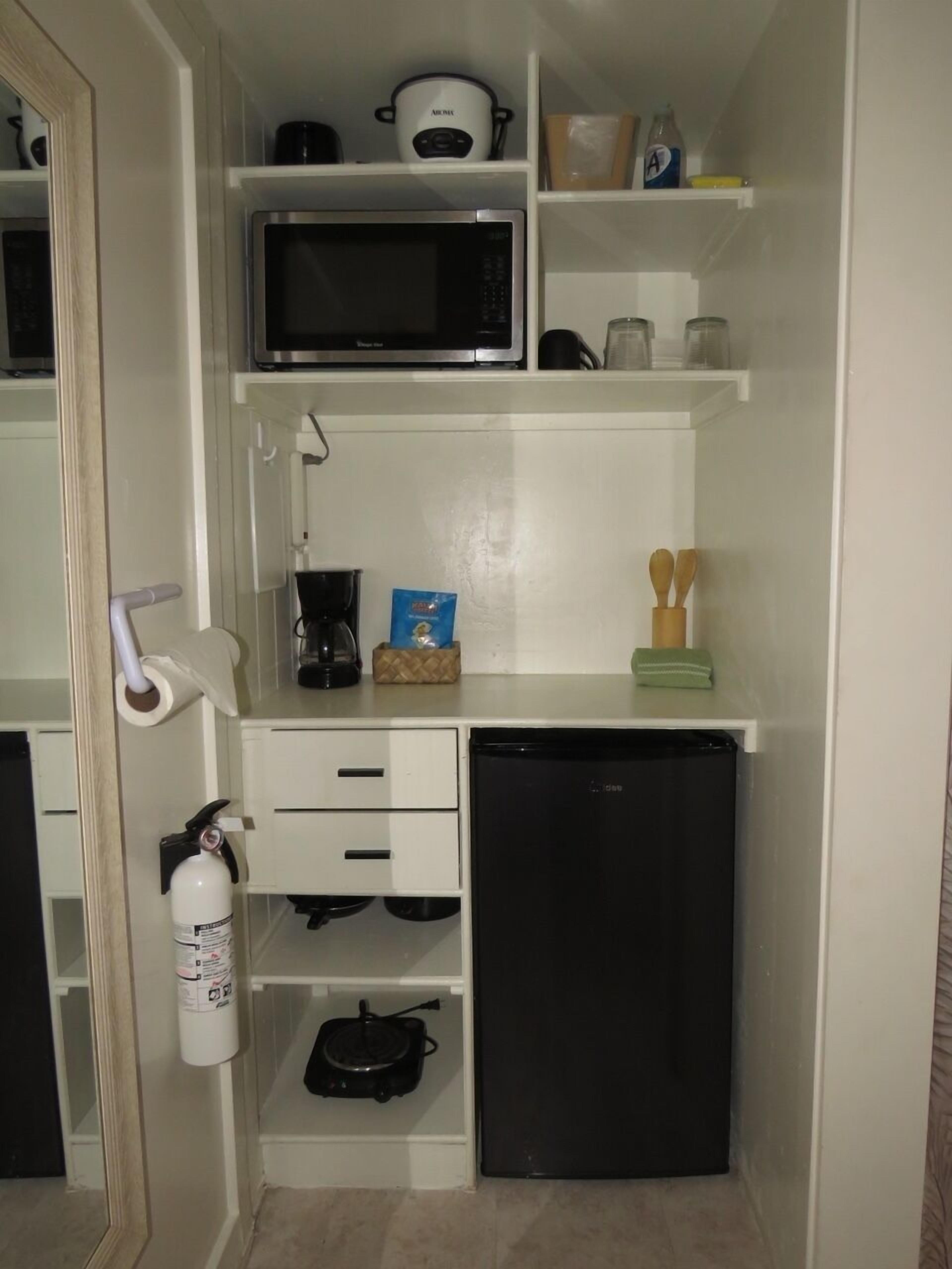 Eine kleine Küchenzeile mit Mikrowelle, Kaffeemaschine und einem kleinen Kühlschrank.