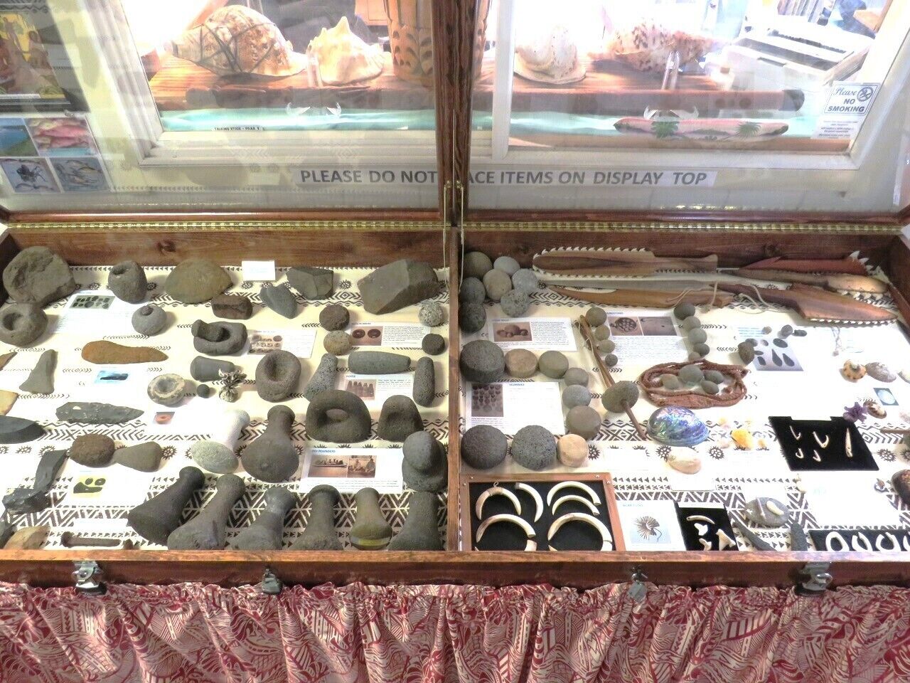 A display case with various stone artifacts and jewelry, including rings and bracelets.