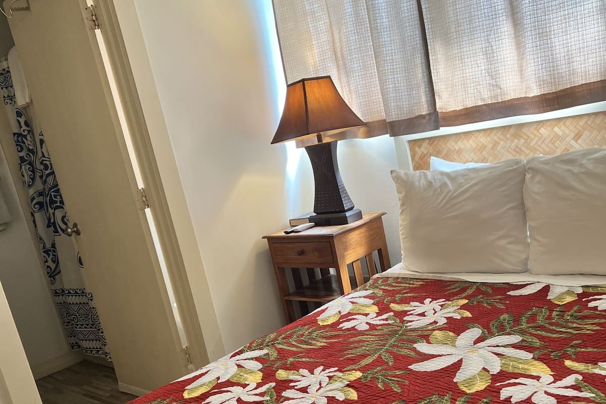 Un dormitorio con colcha floral, lámpara de noche y mesita de madera.